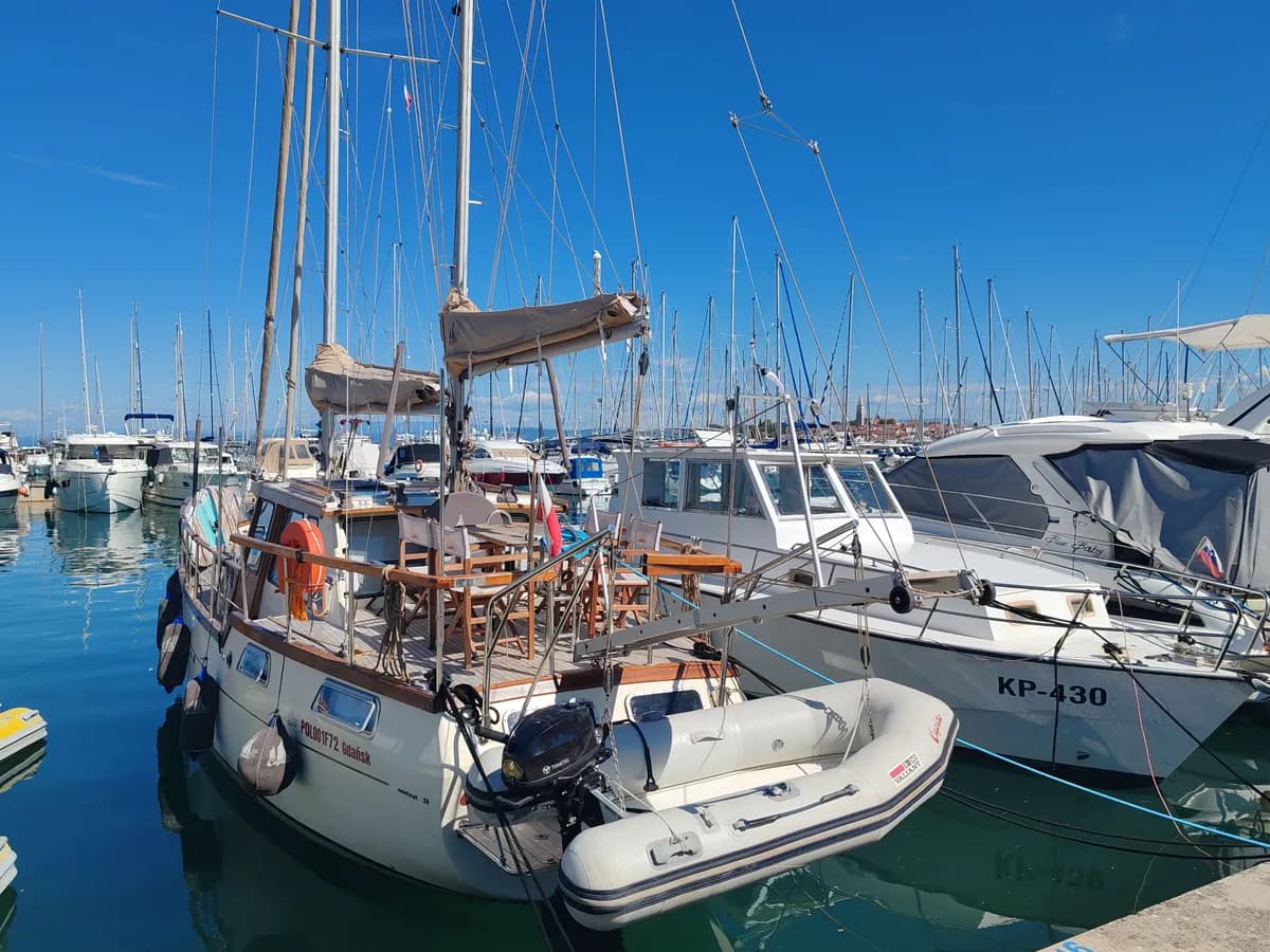 Immagine di esempio BookNoFees: barche a vela con ponti e alberi in legno ormeggiate a un pontile del porto