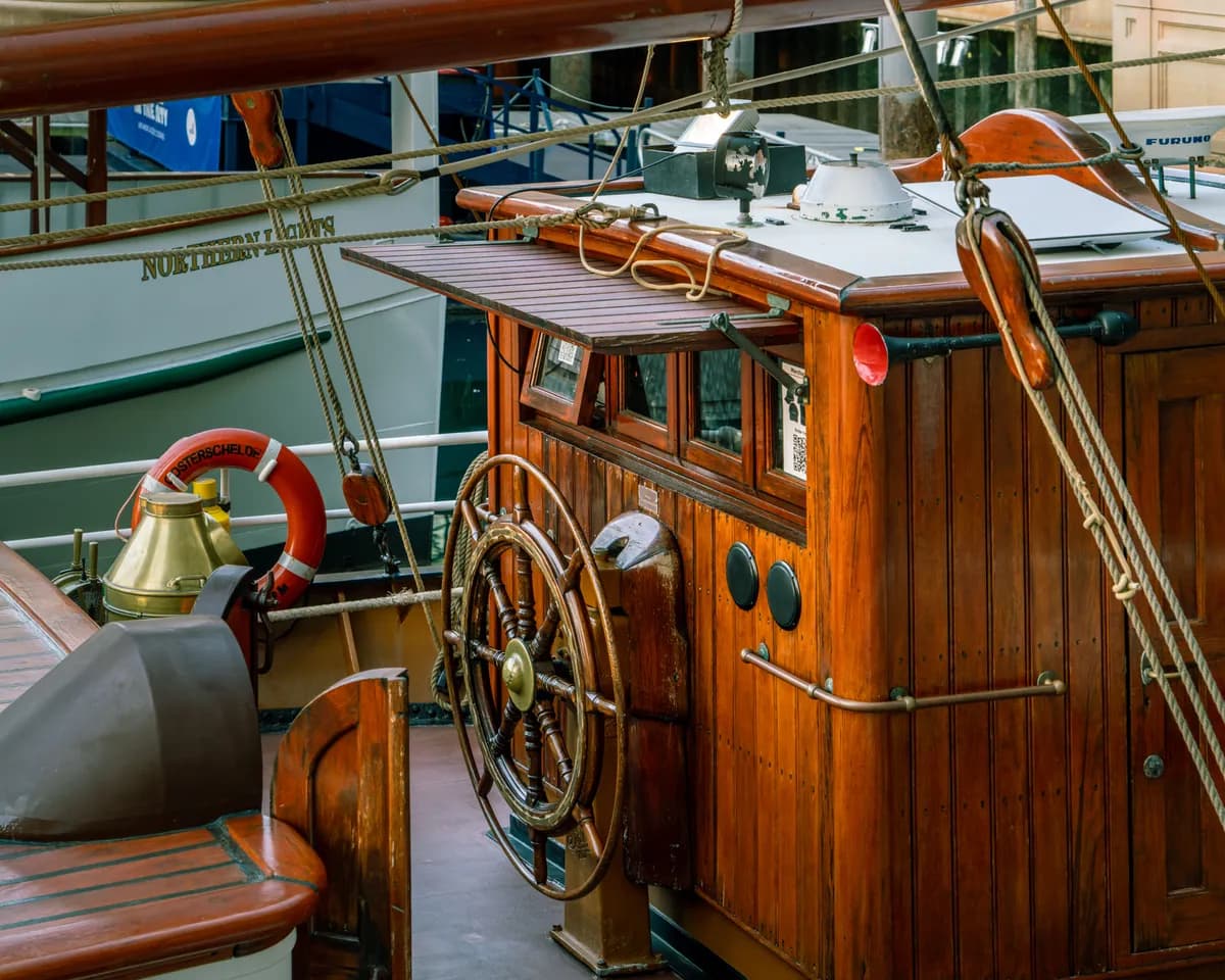Immagine di esempio BookNoFees: cabina in legno di una barca con timone e salvagente