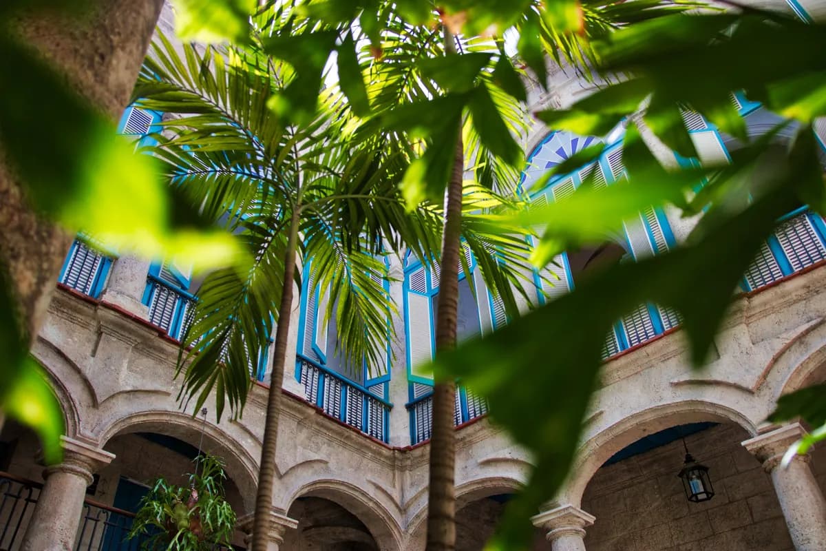 Immagine di esempio BookNoFees: cortile tropicale con palme e balconi storici a Cuba
