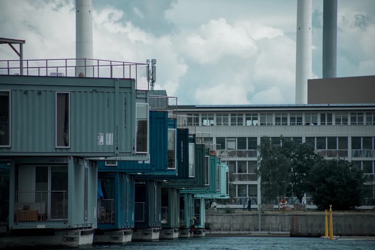 Immagine di esempio BookNoFees: edifici residenziali colorati costruiti con container, con una passerella in riva all’acqua