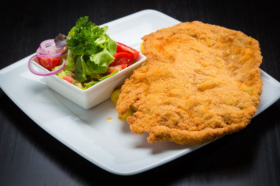 BookNoFees: Foto di esempio: Cotoletta impanata con contorno di insalata su un piatto bianco