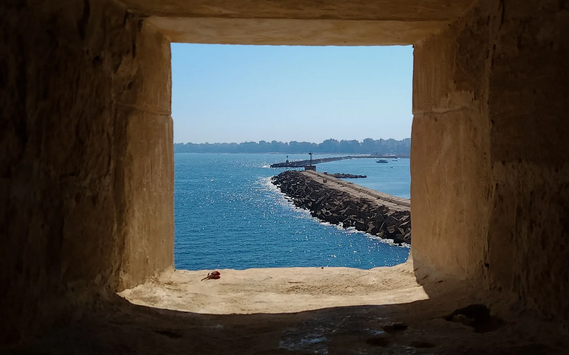 Vista sul mare ad Alessandria attraverso una storica finestra in pietra