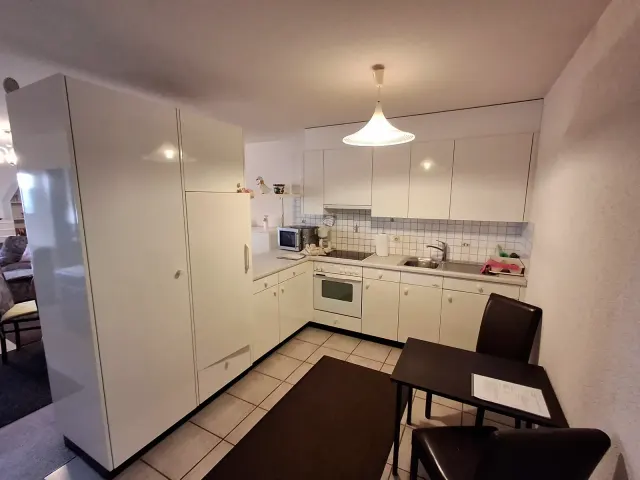 BookNoFees: casa vacanza a Gailingen, Baden-Württemberg, Germania – Cucina con mobili bianchi, fornelli, lavello, forno a microonde e un tavolino da pranzo con sedie