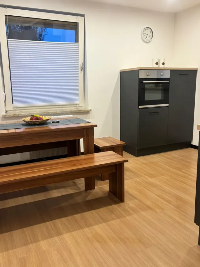 BookNoFees: casa vacanza a Bodenwerder – Cucina con tavolo da pranzo in legno, panca, forno da incasso e finestra con tapparella