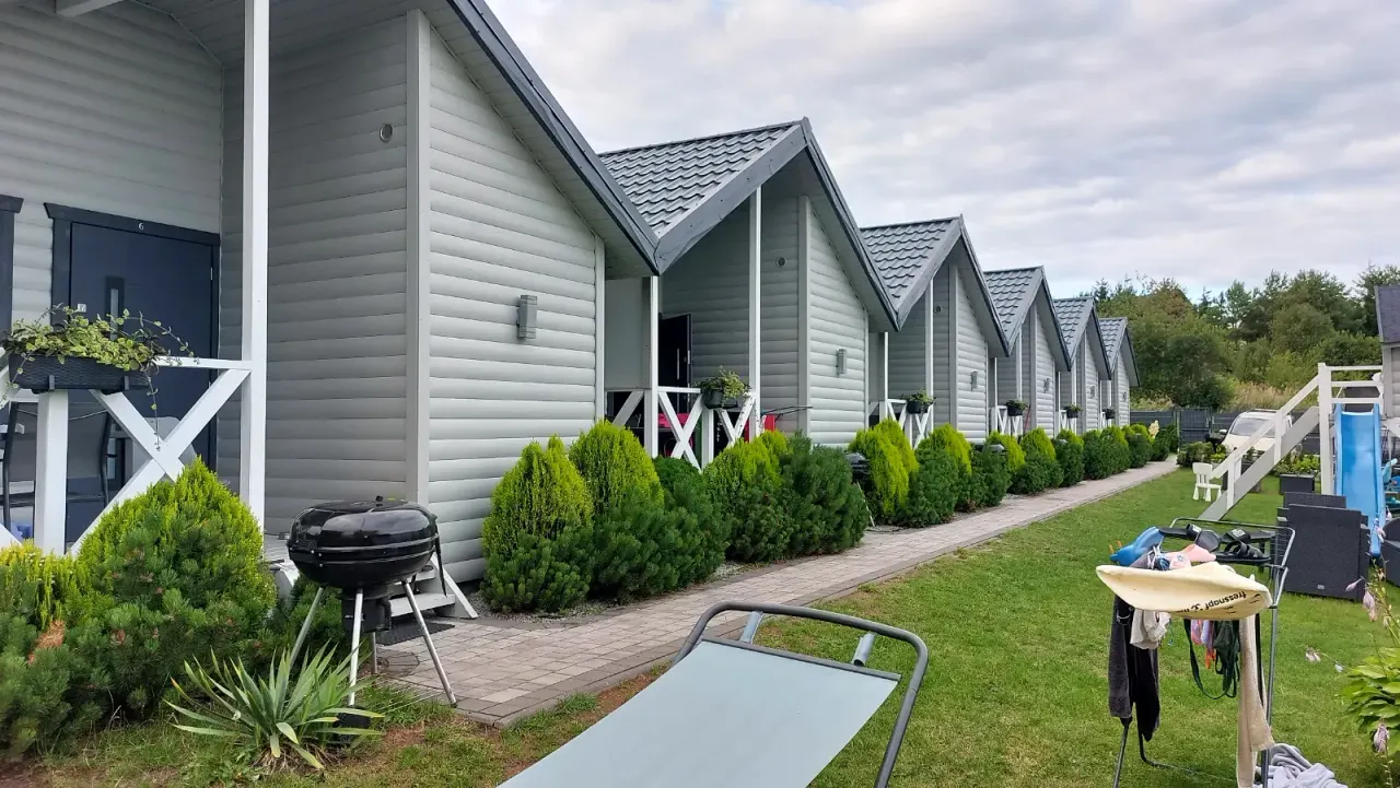 BookNoFees: casa vacanza a Jarosławiec, Polonia – Fila di casette in legno grigio con verande, barbecue e prato verde