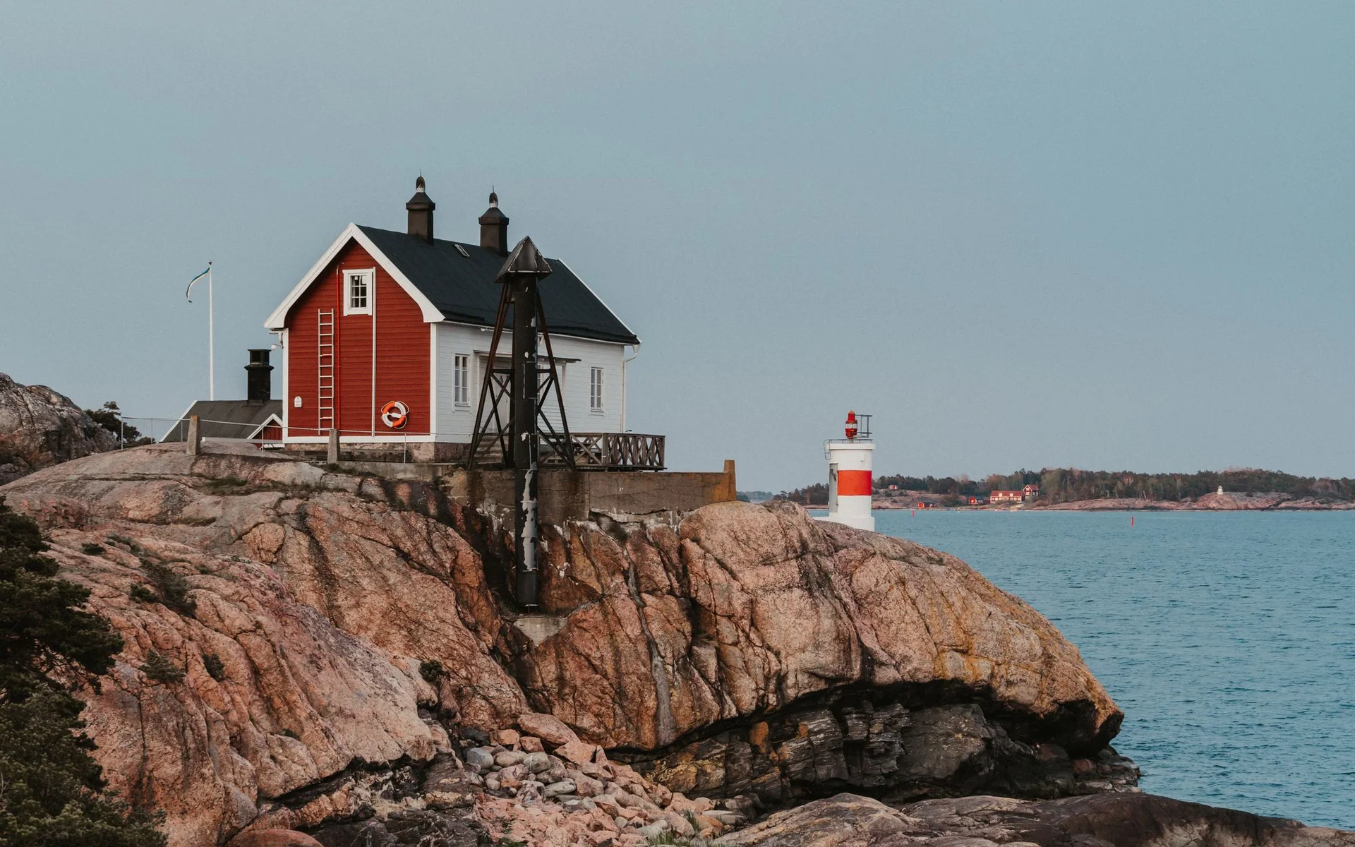 Casa rossa e faro sulla costa rocciosa della Svezia