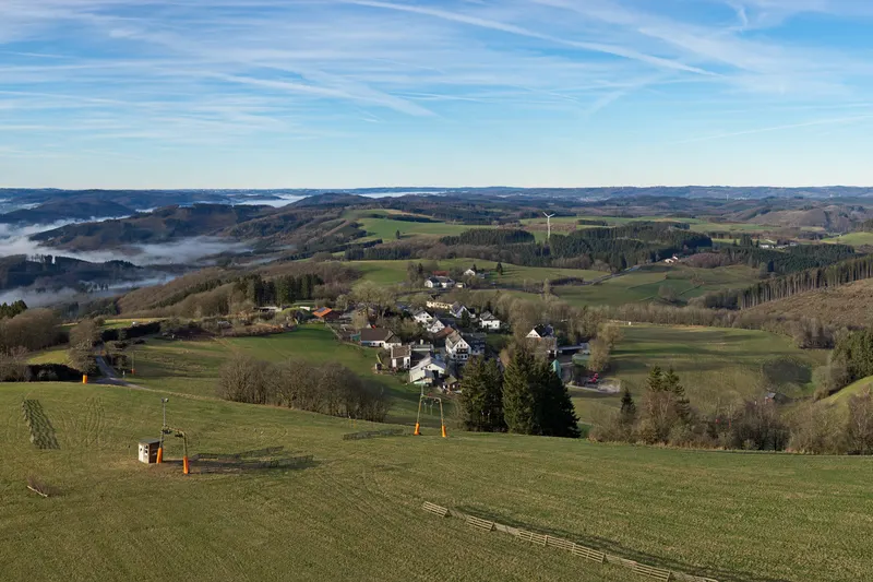Wildewiese sulle colline del Sauerland, con uno skilift sul prato e il paese ai piedi della collina